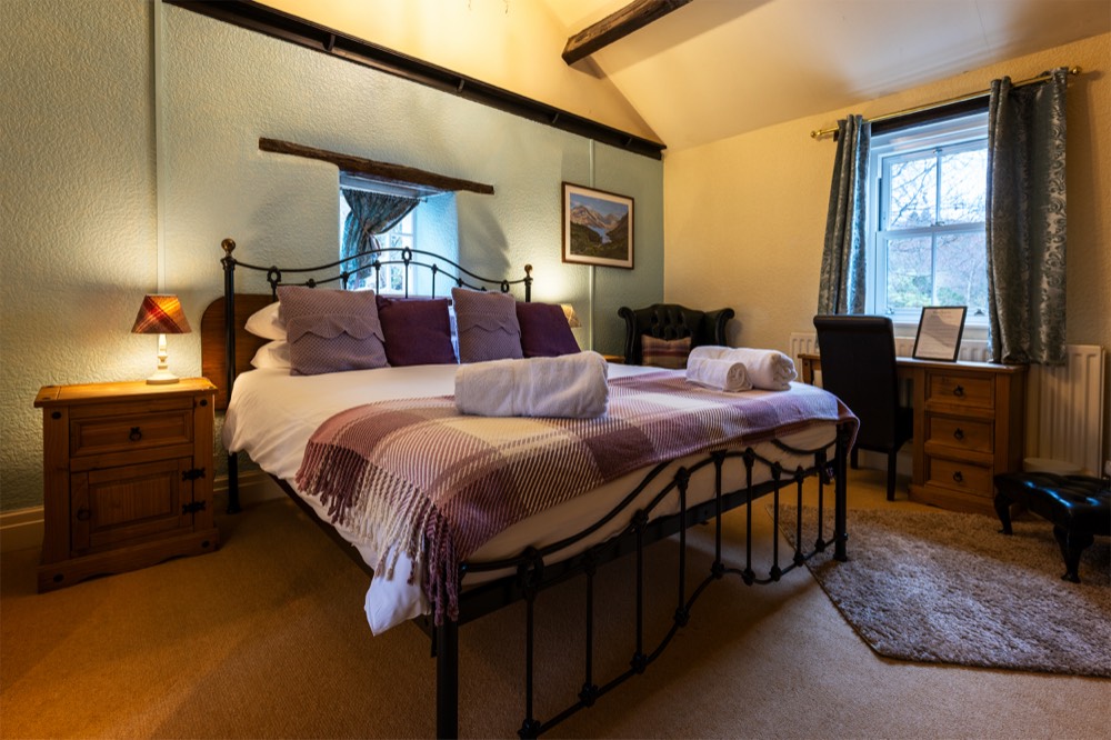Double room at The Strands, with iron bed frame and Lake District landscape print above the headboard